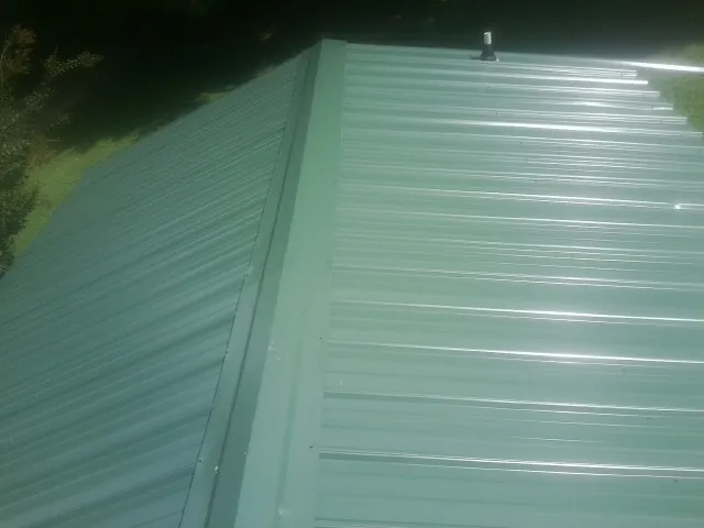 New green metal panels meeting at the ridge of a roof — Flat Roof Repair work by our crew in Clarks Hill