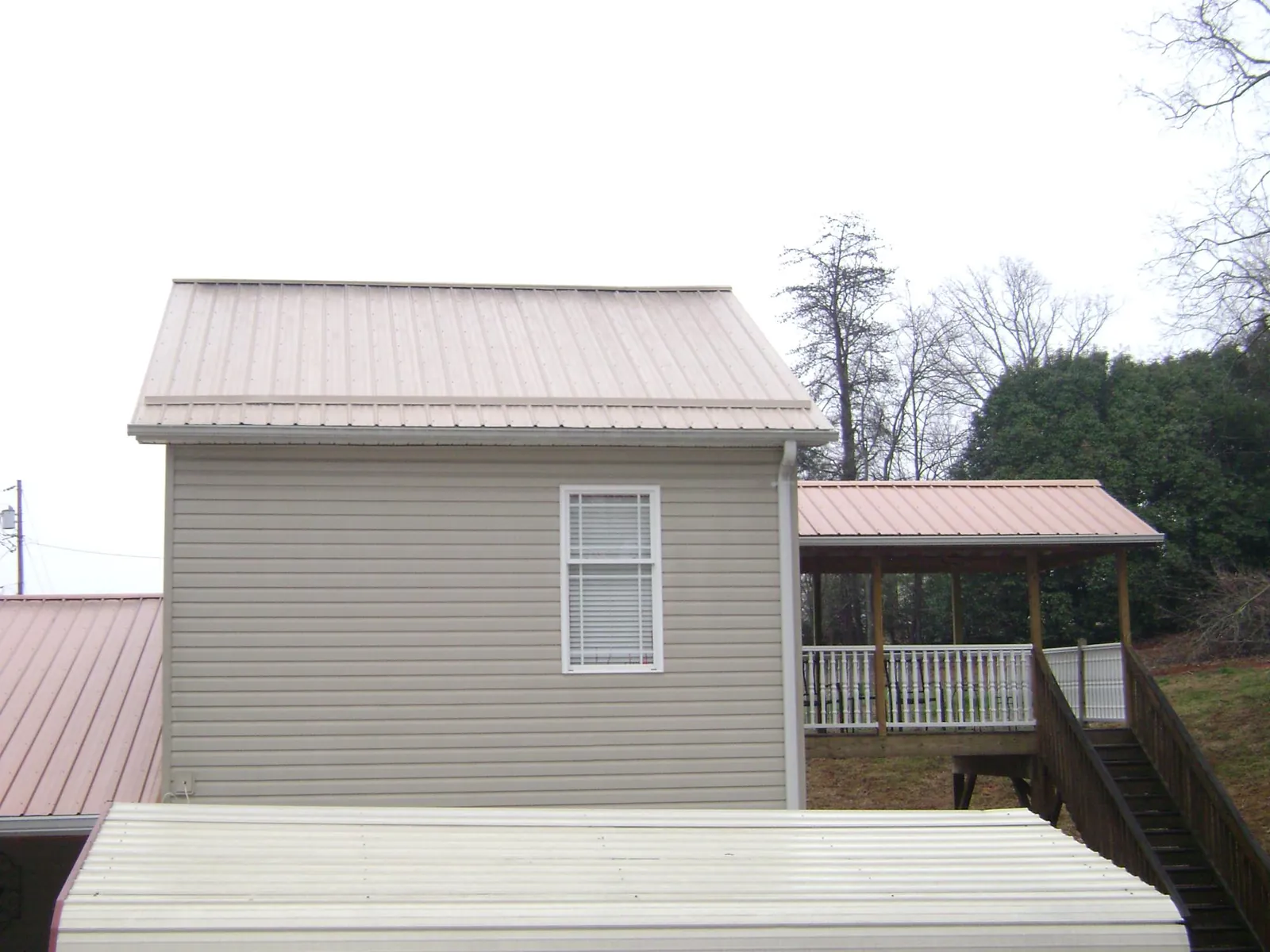 Tan metal roofs on a two story addition and attached porch, from a Roof Replacement job in Clarks Hill
