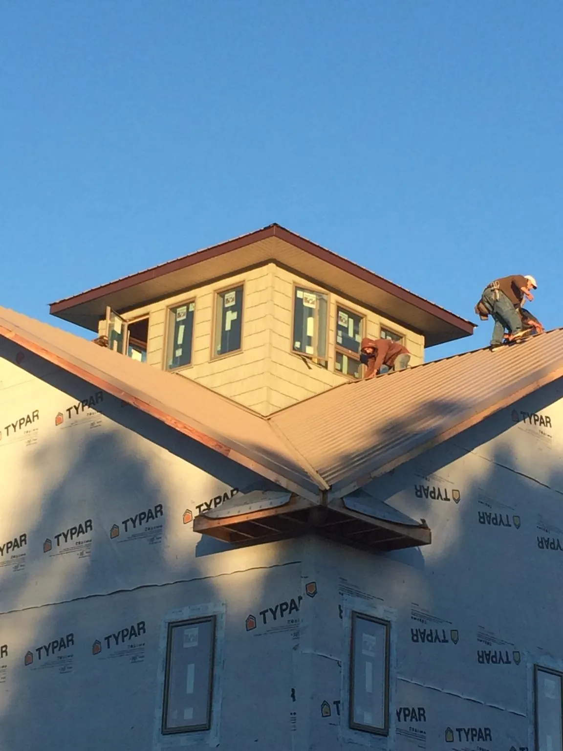 Roofers working around a rooftop cupola on a new metal roof at sunset — Roof Waterproofing in Clarks Hill by Roofing Brothers